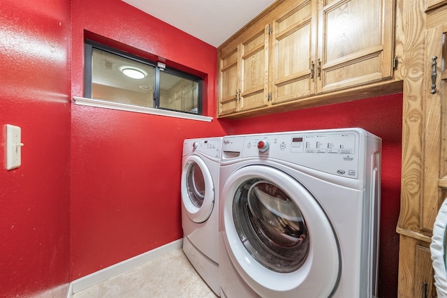 clothes washing area featuring washer and dryer, light tile patterned floors, and cabinets