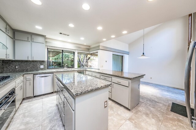 kitchen with decorative backsplash, recessed lighting, a kitchen island, and appliances with stainless steel finishes