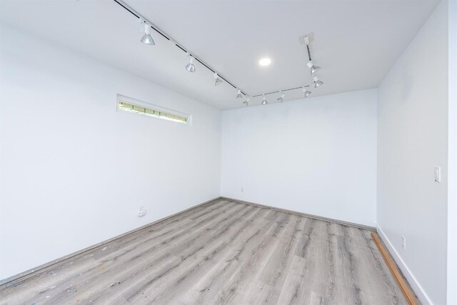 unfurnished room with rail lighting, baseboards, and light wood-style floors