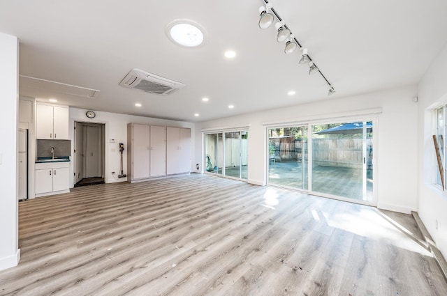 unfurnished living room with sink and light hardwood / wood-style floors