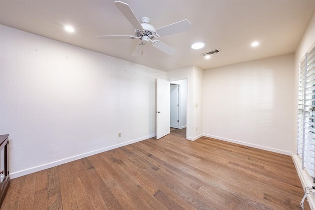 unfurnished room featuring baseboards, visible vents, wood finished floors, and ceiling fan