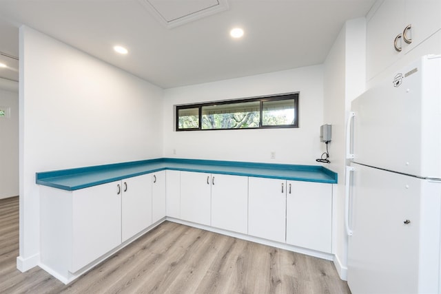 kitchen with light hardwood / wood-style floors, white fridge, and white cabinetry