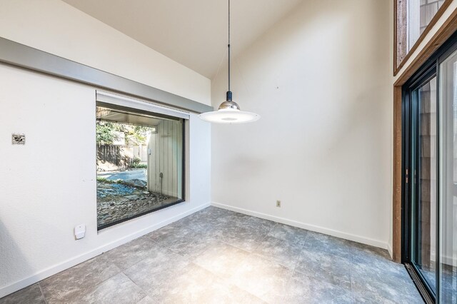 unfurnished dining area featuring high vaulted ceiling and baseboards