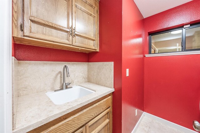 laundry room with baseboards, a sink, and tile patterned floors