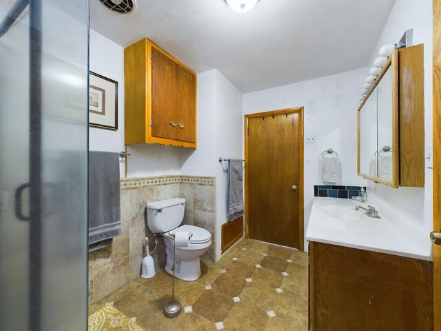 bathroom featuring tile patterned floors, vanity, tile walls, and toilet