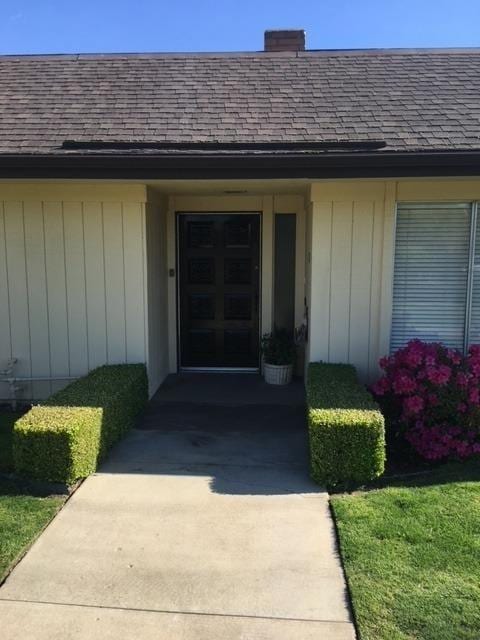 doorway to property featuring concrete driveway and roof with shingles