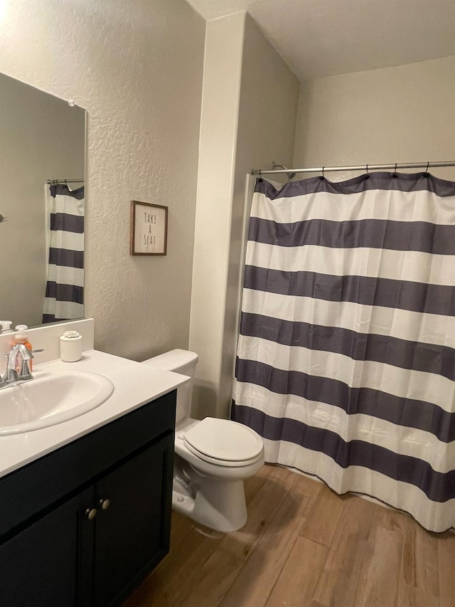 bathroom featuring hardwood / wood-style floors, vanity, walk in shower, and toilet