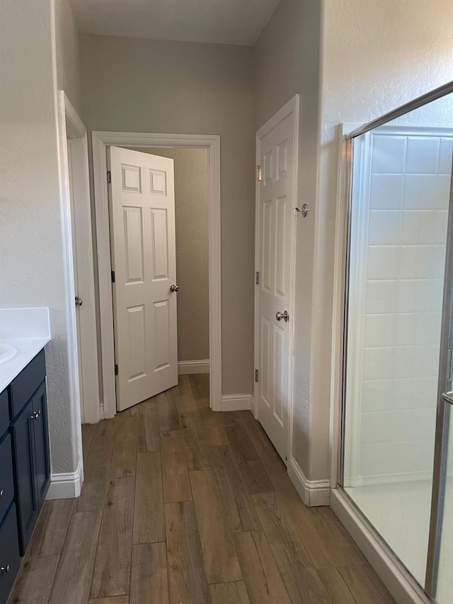 bathroom featuring a shower with door, vanity, and wood-type flooring