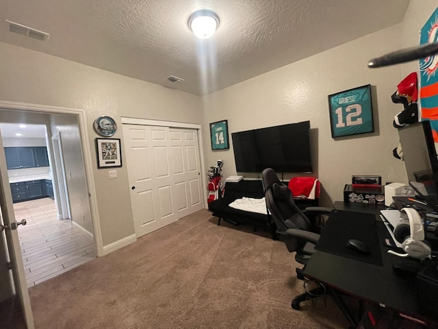 carpeted office space featuring a textured ceiling