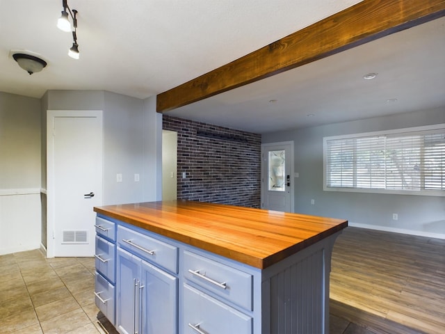 kitchen with light hardwood / wood-style floors, a kitchen island, beam ceiling, and wood counters