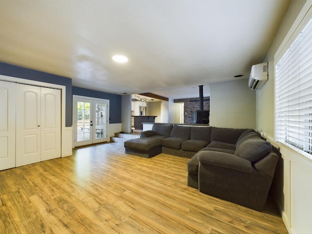 living room featuring french doors, light hardwood / wood-style floors, and a wall unit AC