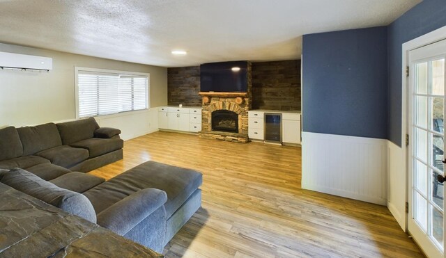 living room featuring light wood-type flooring, plenty of natural light, and a wall unit AC