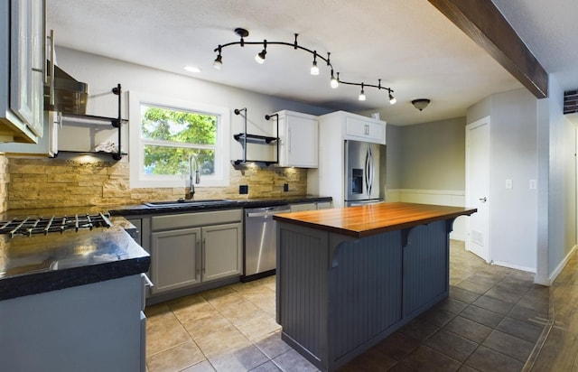 kitchen featuring sink, backsplash, stainless steel appliances, a center island, and wood counters