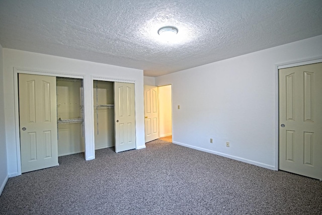 unfurnished bedroom with multiple closets, a textured ceiling, and carpet