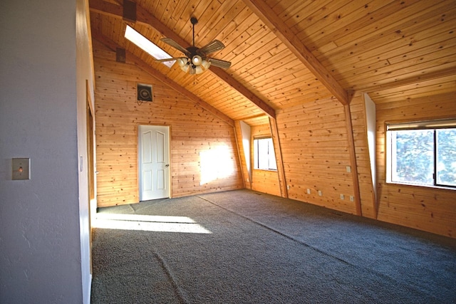 additional living space featuring ceiling fan, vaulted ceiling with skylight, wooden walls, carpet, and wooden ceiling