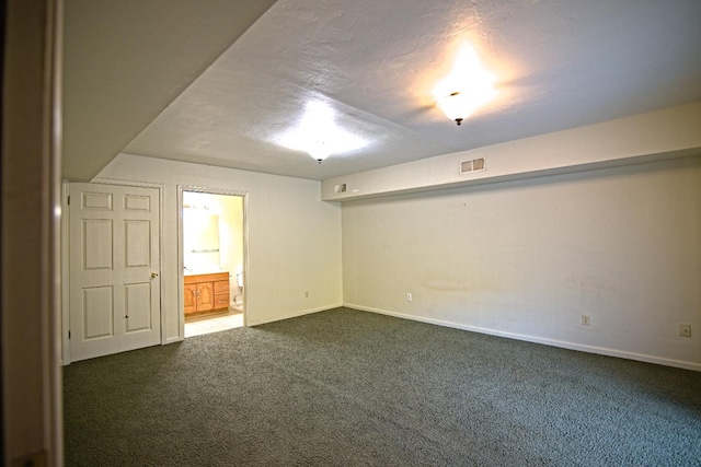 unfurnished room with dark carpet and a textured ceiling