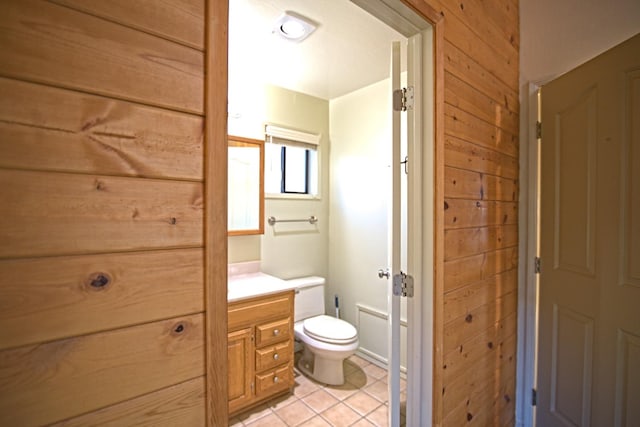 bathroom featuring wooden walls, vanity, tile patterned flooring, and toilet