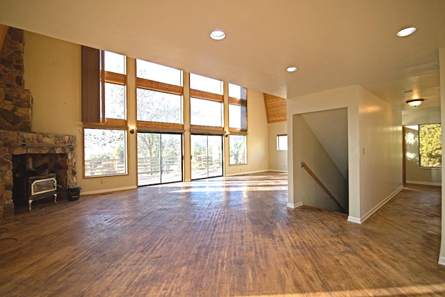 unfurnished living room with dark hardwood / wood-style floors, a high ceiling, and a wood stove