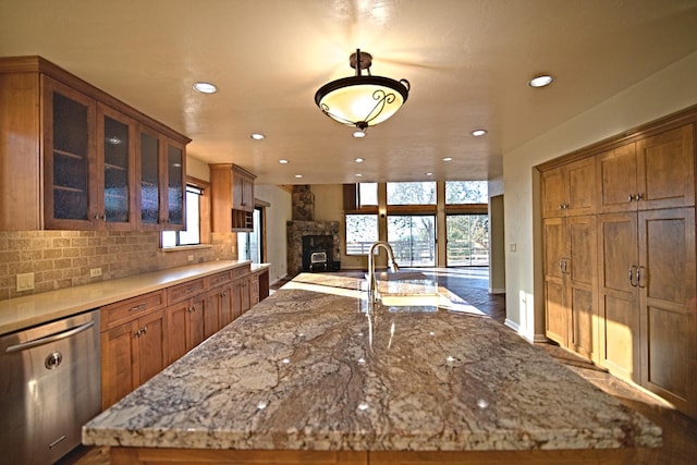 kitchen featuring light stone countertops, plenty of natural light, a fireplace, and stainless steel dishwasher