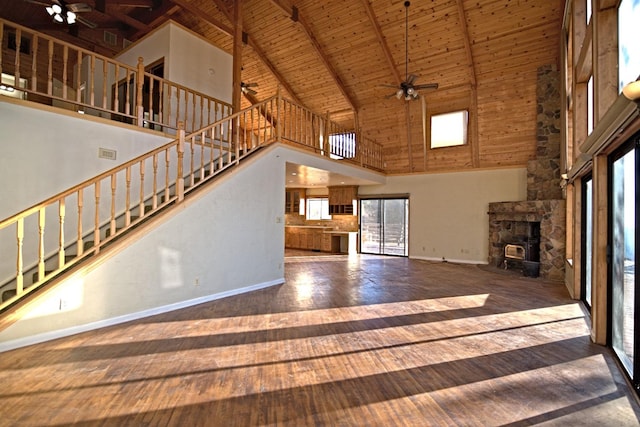 unfurnished living room with wood ceiling, beam ceiling, a wood stove, high vaulted ceiling, and hardwood / wood-style flooring