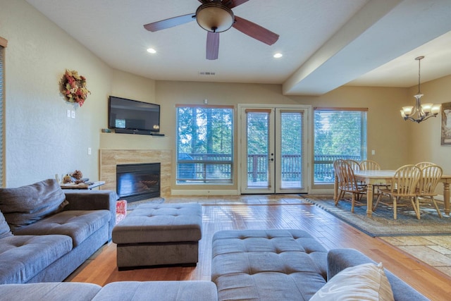 living room featuring a fireplace, ceiling fan with notable chandelier, hardwood / wood-style floors, and a healthy amount of sunlight