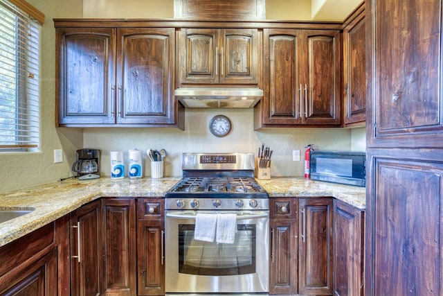 kitchen with light stone countertops, extractor fan, and appliances with stainless steel finishes