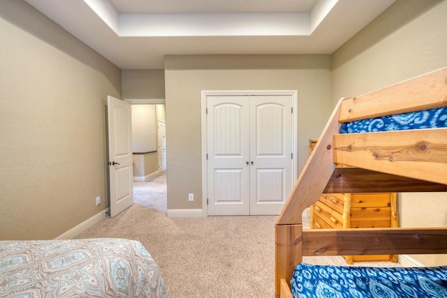 bedroom featuring light carpet, a closet, and a tray ceiling