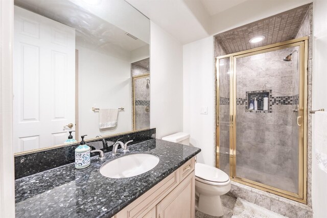 bathroom featuring tile patterned flooring, vanity, toilet, and a shower with door