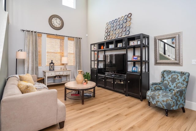 living room with a wealth of natural light, a high ceiling, and hardwood / wood-style flooring