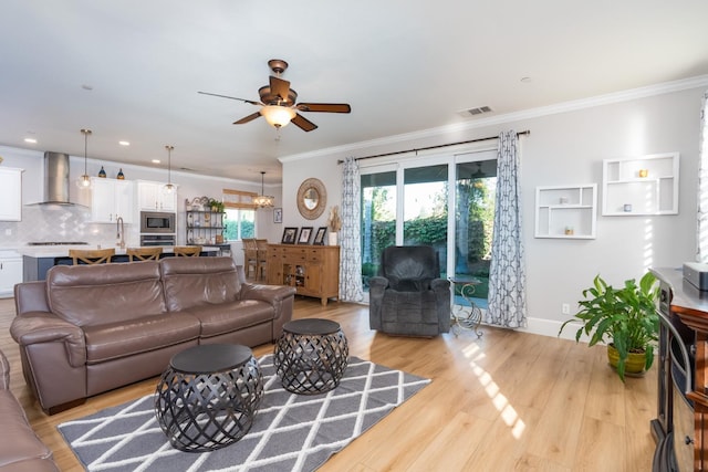 living room with light hardwood / wood-style flooring, ceiling fan, and crown molding