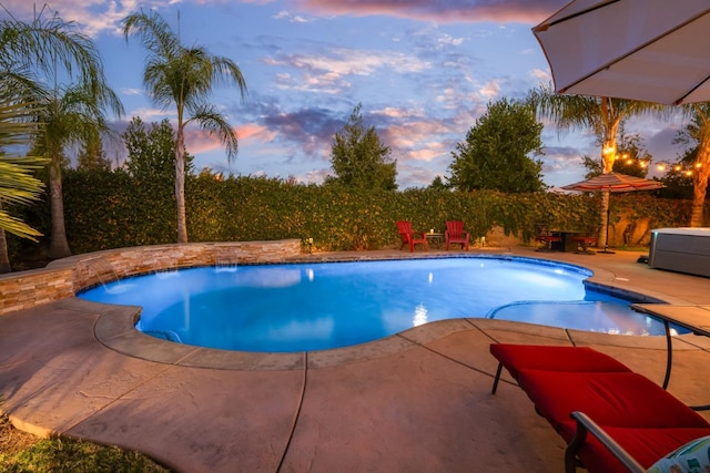 pool at dusk featuring a patio