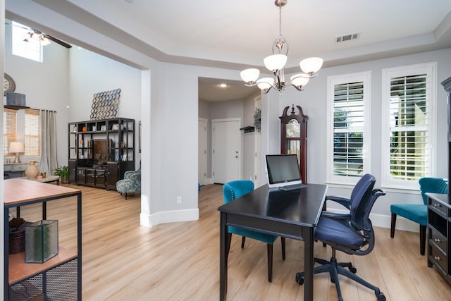 office space featuring light hardwood / wood-style flooring and ceiling fan with notable chandelier