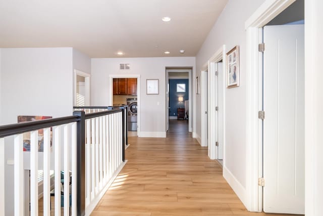 hall with washer / dryer and light hardwood / wood-style flooring