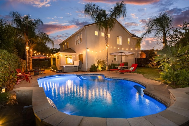 pool at dusk featuring a patio area