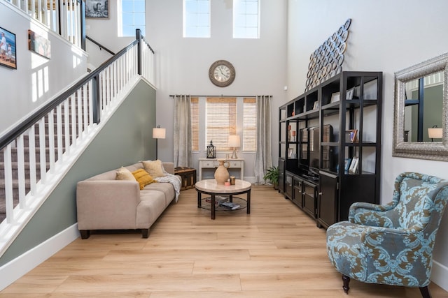 living room with light hardwood / wood-style flooring and a towering ceiling