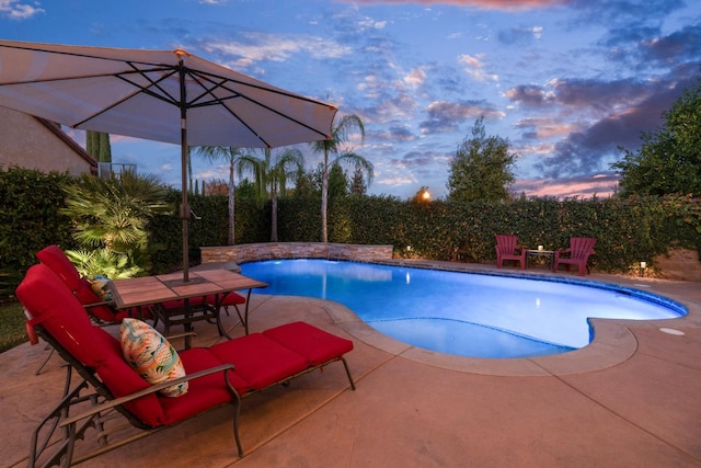 pool at dusk with a patio area