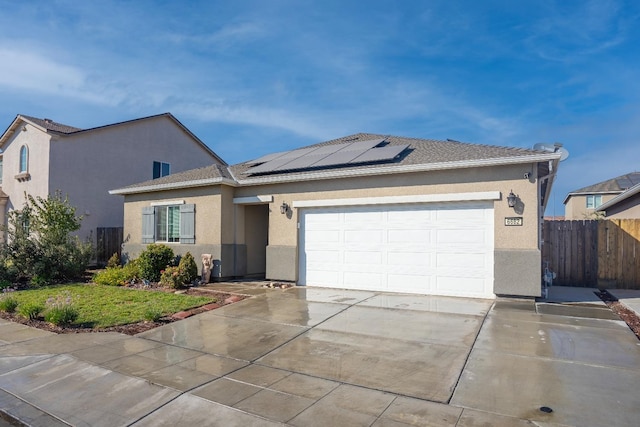 ranch-style house with a garage and solar panels