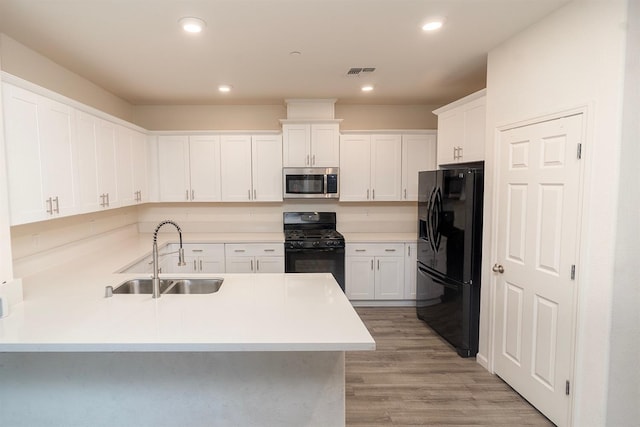 kitchen with sink, white cabinetry, black appliances, kitchen peninsula, and light wood-type flooring