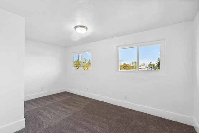 empty room with baseboards and dark colored carpet
