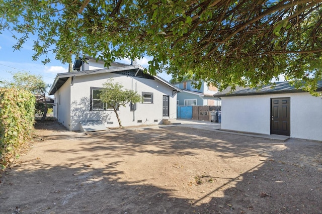 back of property with stucco siding and fence
