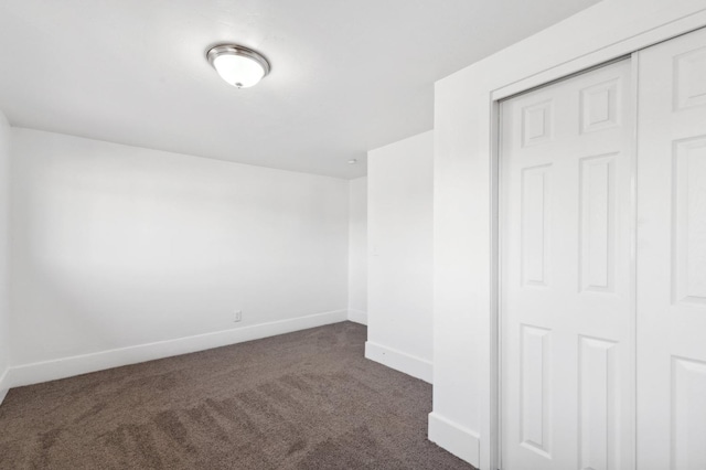 interior space featuring baseboards and dark colored carpet