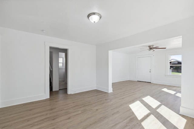spare room with ceiling fan, baseboards, light wood-style flooring, and plenty of natural light
