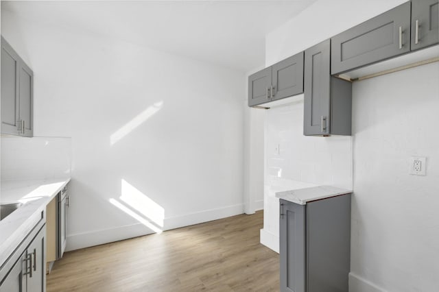 kitchen with backsplash, light wood-type flooring, and gray cabinetry