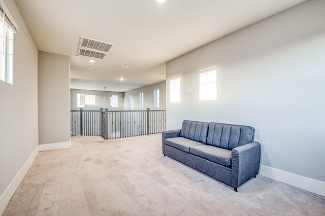 living area featuring baseboards, carpet flooring, visible vents, and plenty of natural light