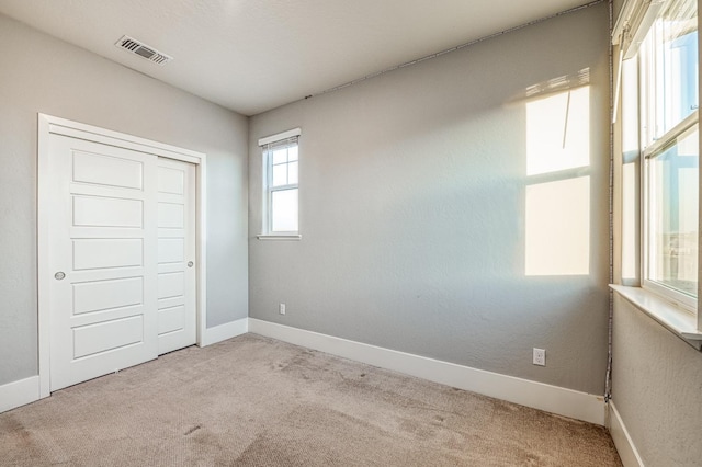 unfurnished bedroom featuring carpet, visible vents, baseboards, and a closet