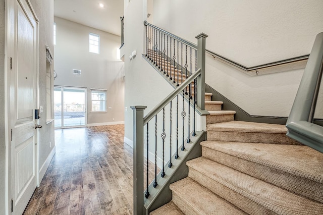 stairs featuring visible vents, wood finished floors, baseboards, and a healthy amount of sunlight
