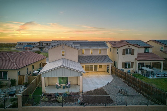 view of front of property featuring roof mounted solar panels, stucco siding, a fenced backyard, and a patio area