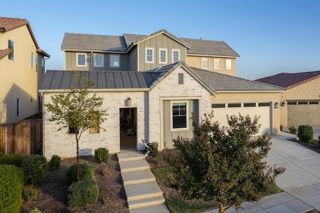 view of front of home with an attached garage, fence, board and batten siding, driveway, and a standing seam roof