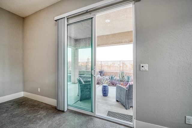 doorway featuring baseboards, carpet, and a textured wall
