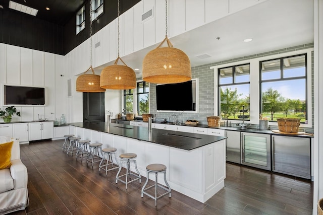 kitchen with visible vents, white cabinetry, a towering ceiling, dark countertops, and dark wood-style floors